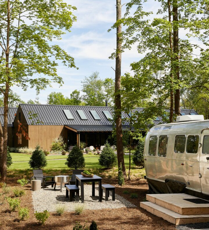 AutoCamp Catskills luxury glamping Airstream in Catskills mountains outdoor wooded area with patio and view of AutoCamp clubhouse