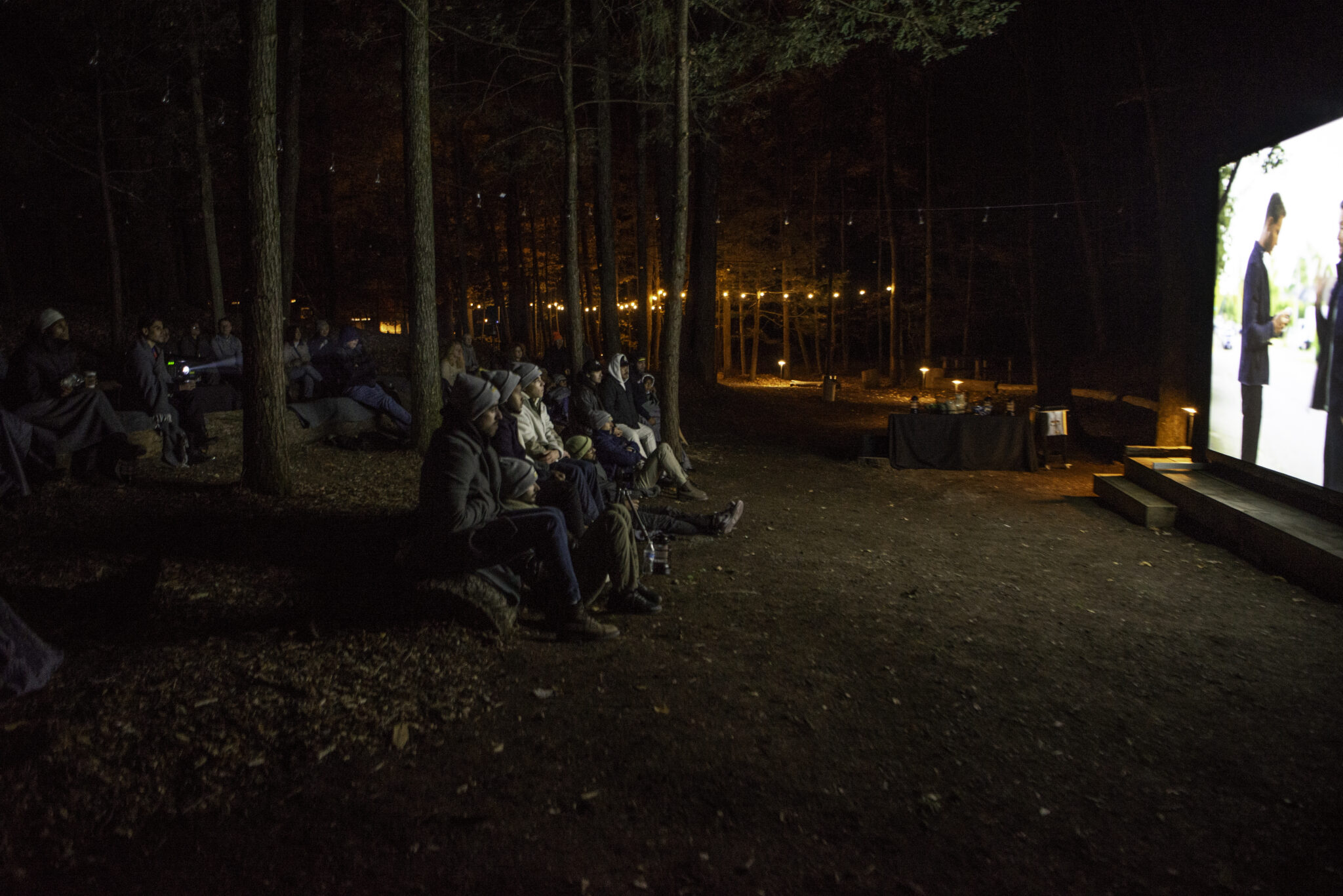 Group of people watching a screen in the woods.