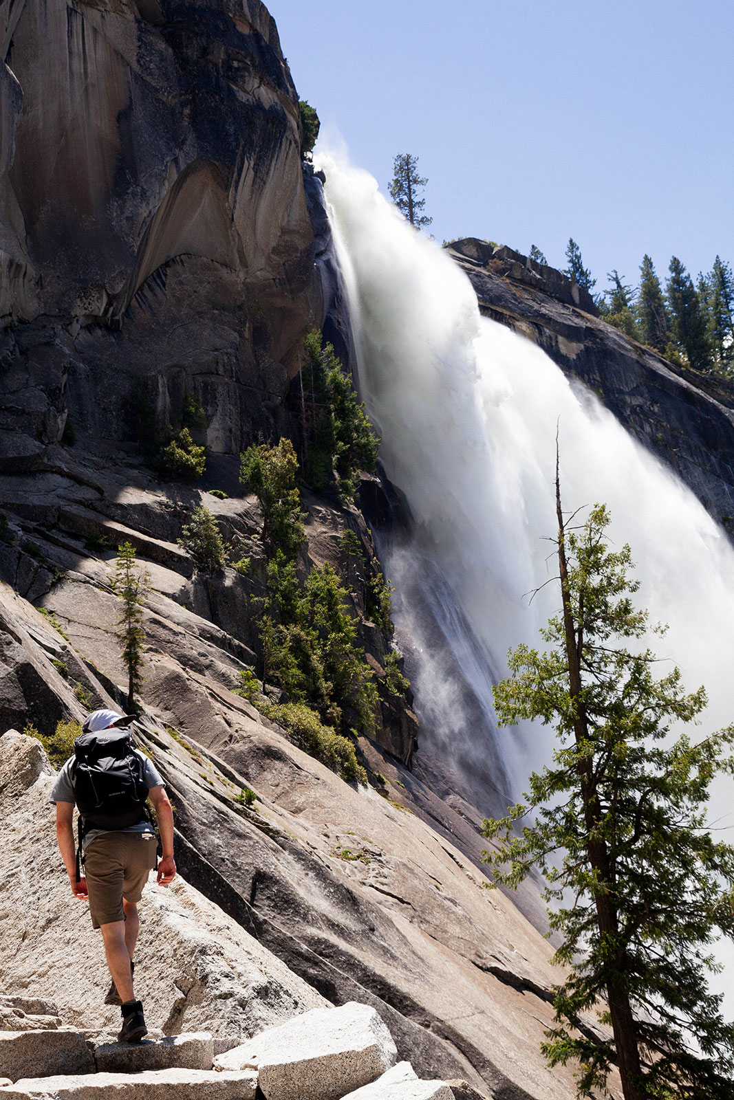 Man hiking rocks near a waterfall