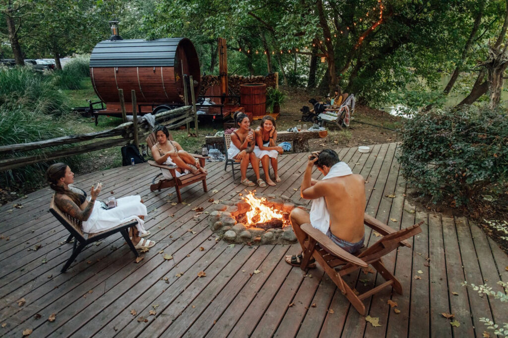 Friends gathered around a fire in the woods on a deck