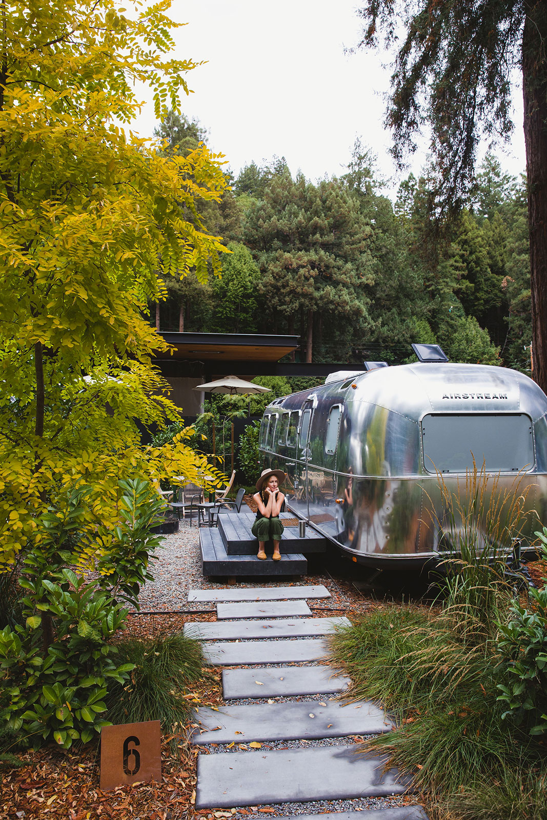 Woman sitting in nature next to an Airstream