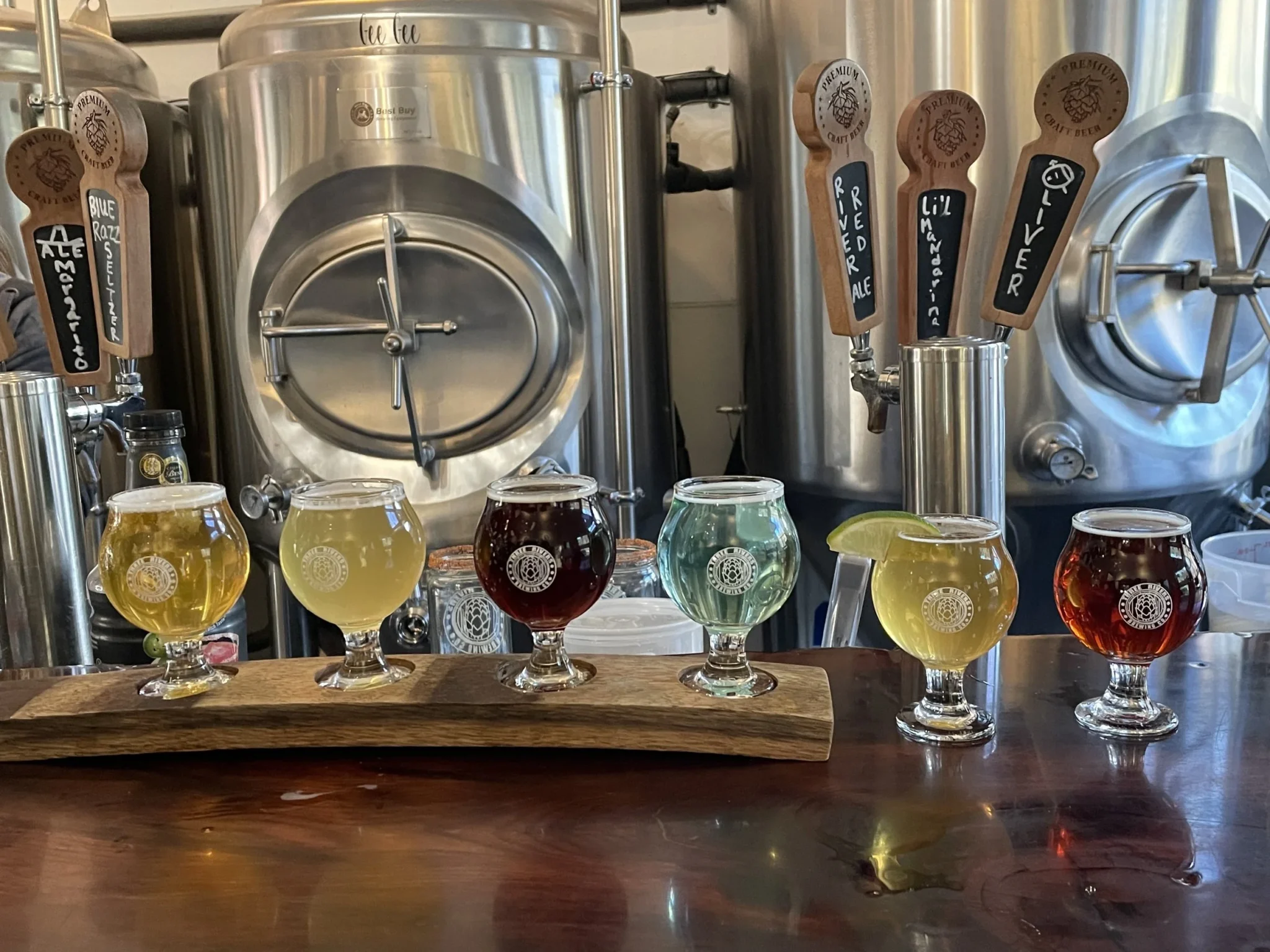 Six types of beer in glasses ready for a tasting with beer vats in the background