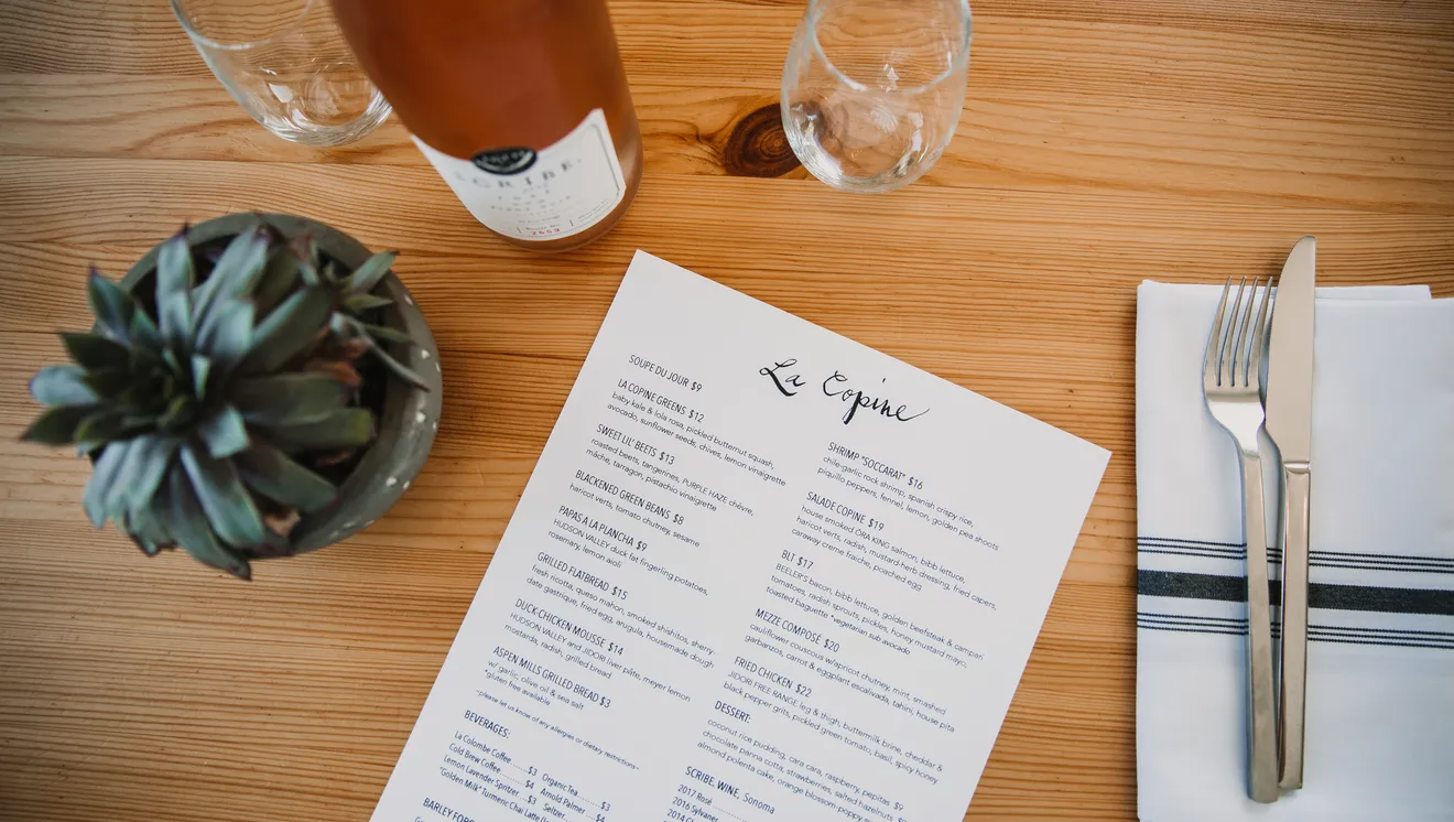 La Copine restaurant menu on a table with place setting and small succulent plant