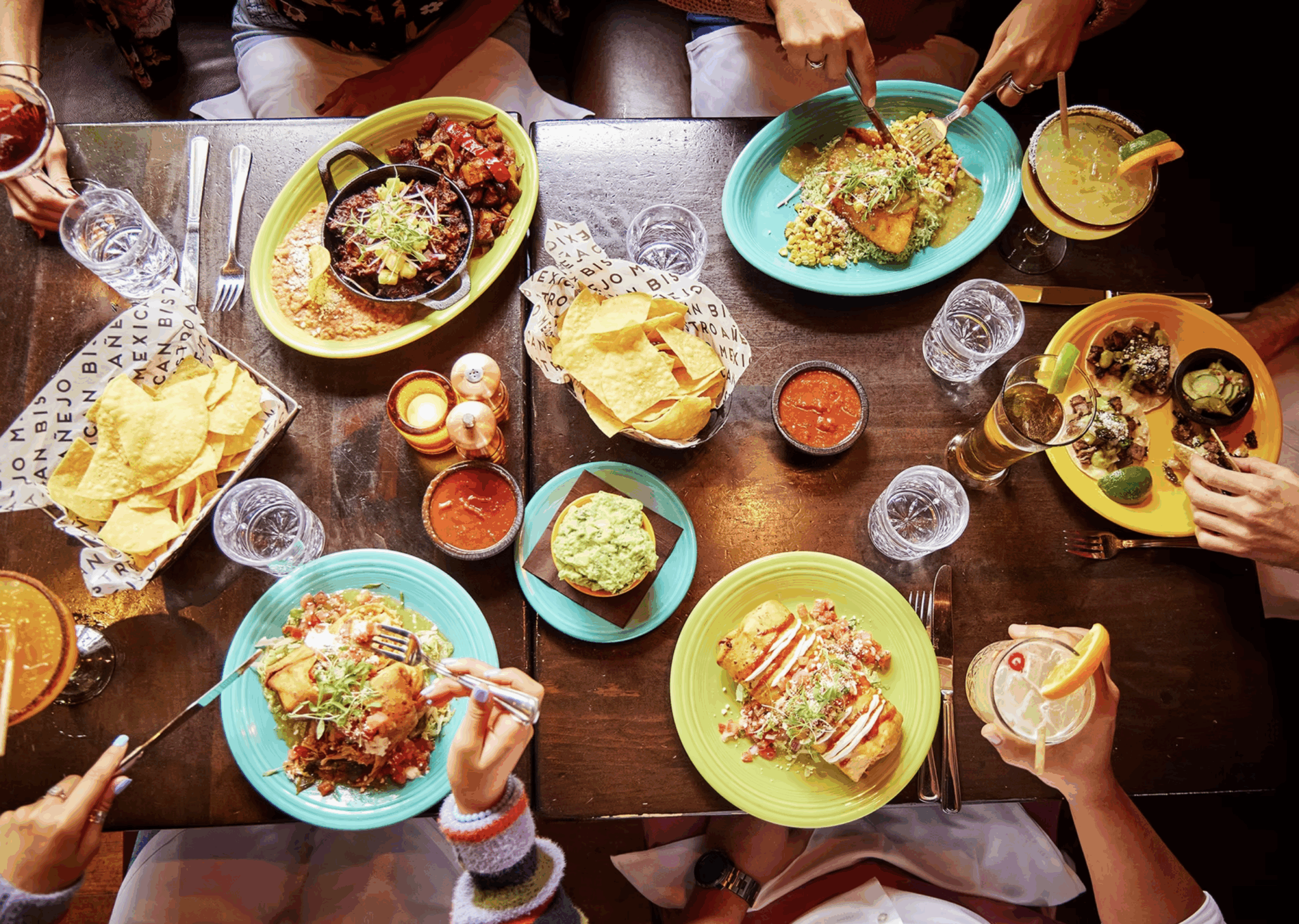 friends having Mexican food and margaritas with the focus on colorful plates of burritos and nachos