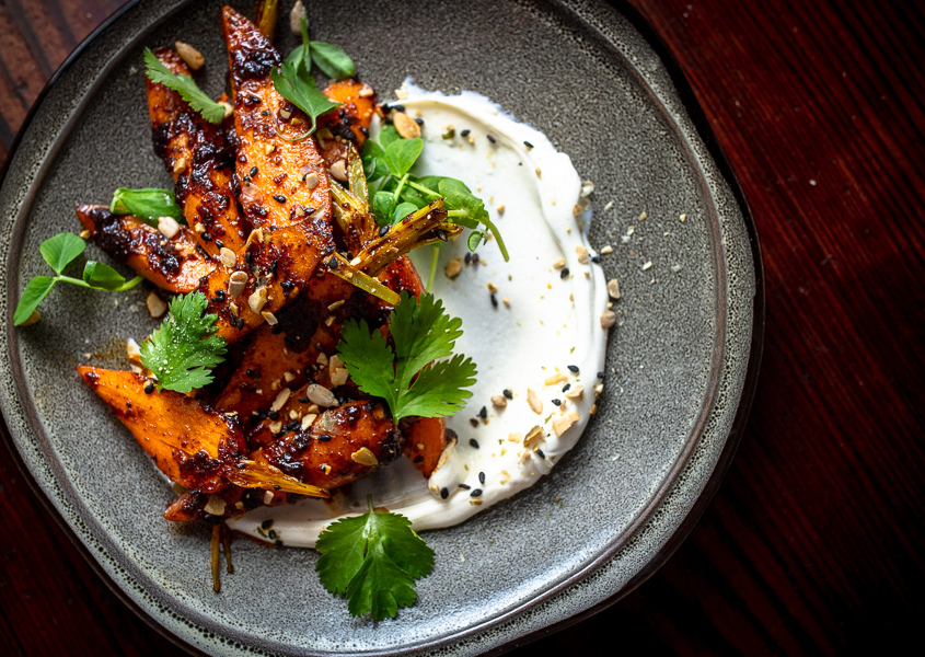 beautiful black ceramic dinner plate with main dish and creamy base sauce