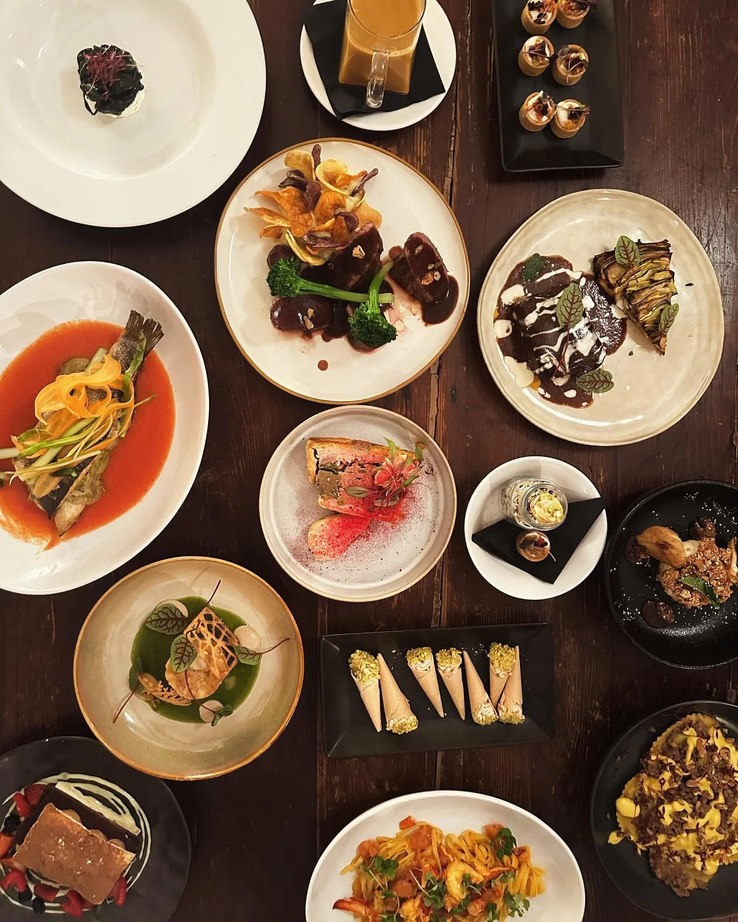 beautiful dinner spread with various dinner and dessert dishes on a dark wooden table