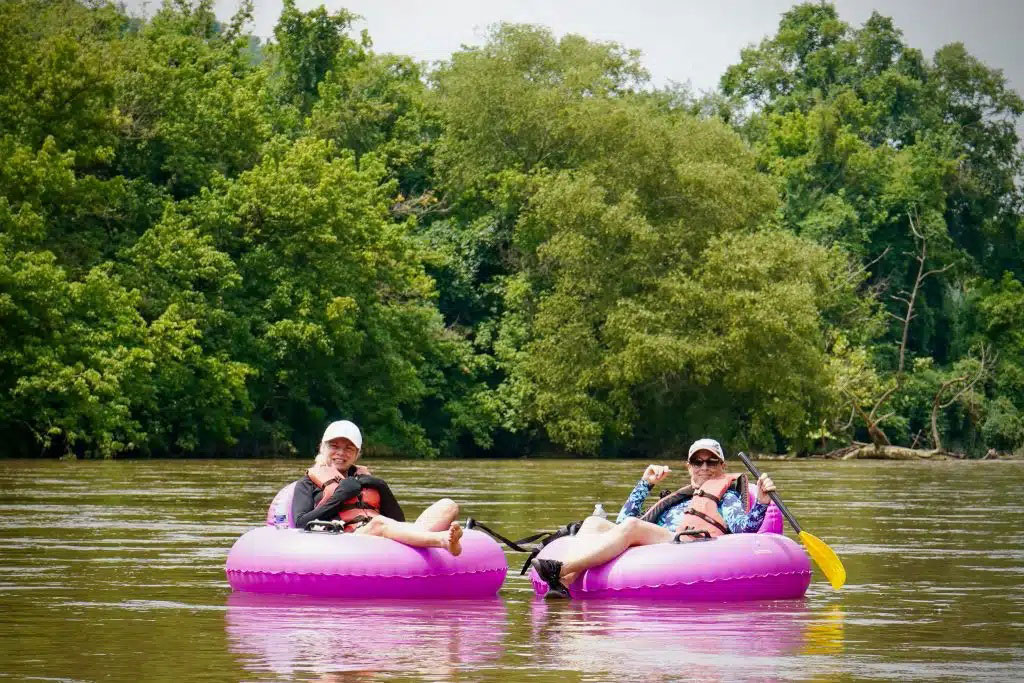 Friends floating down the river on pink tubes