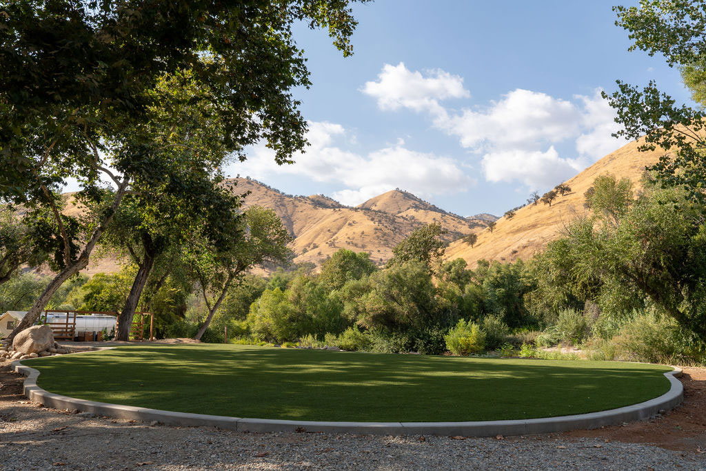 Outdoor meeting and gathering areas with trees and golden hills in the background at AutoCamp Sequoia. Known as Ponderosa Lawn.