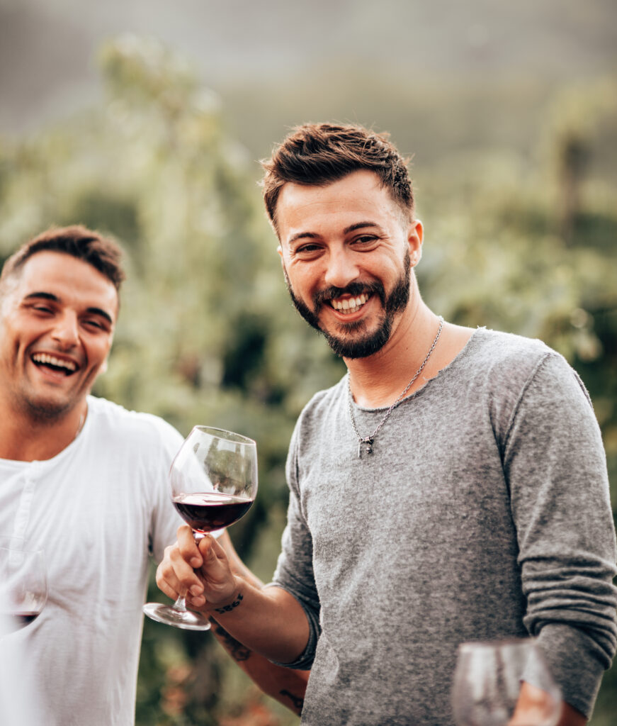 Two men outside drinking wine and smiling