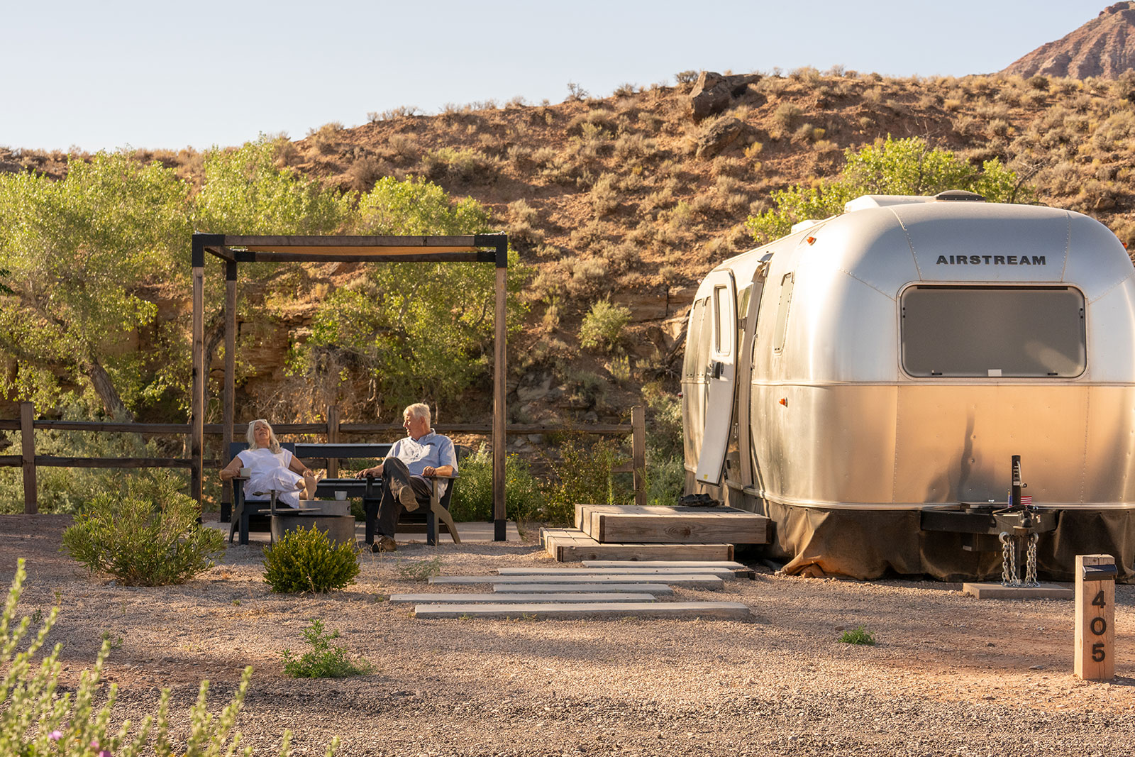 Couple relaxing and sitting outside next to their Airstream at AutoCamp Zion